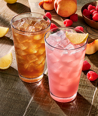 A refreshing glass of Raspberry Lemonade and a tall Iced Tea with ice cubes, served chilled with lemon slices and fresh mint.