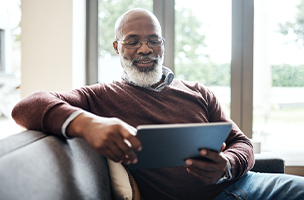 Person seated in a chair looking at a tablet while smiling