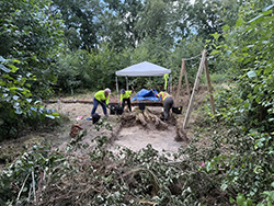 A team of Terracon archaeologists performing a search in a field under a tent