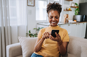 Person seated on a couch using a mobile phone.