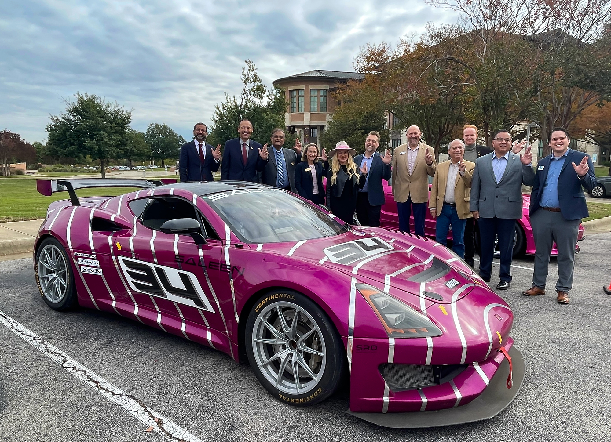 txst leadership next to a purple race car