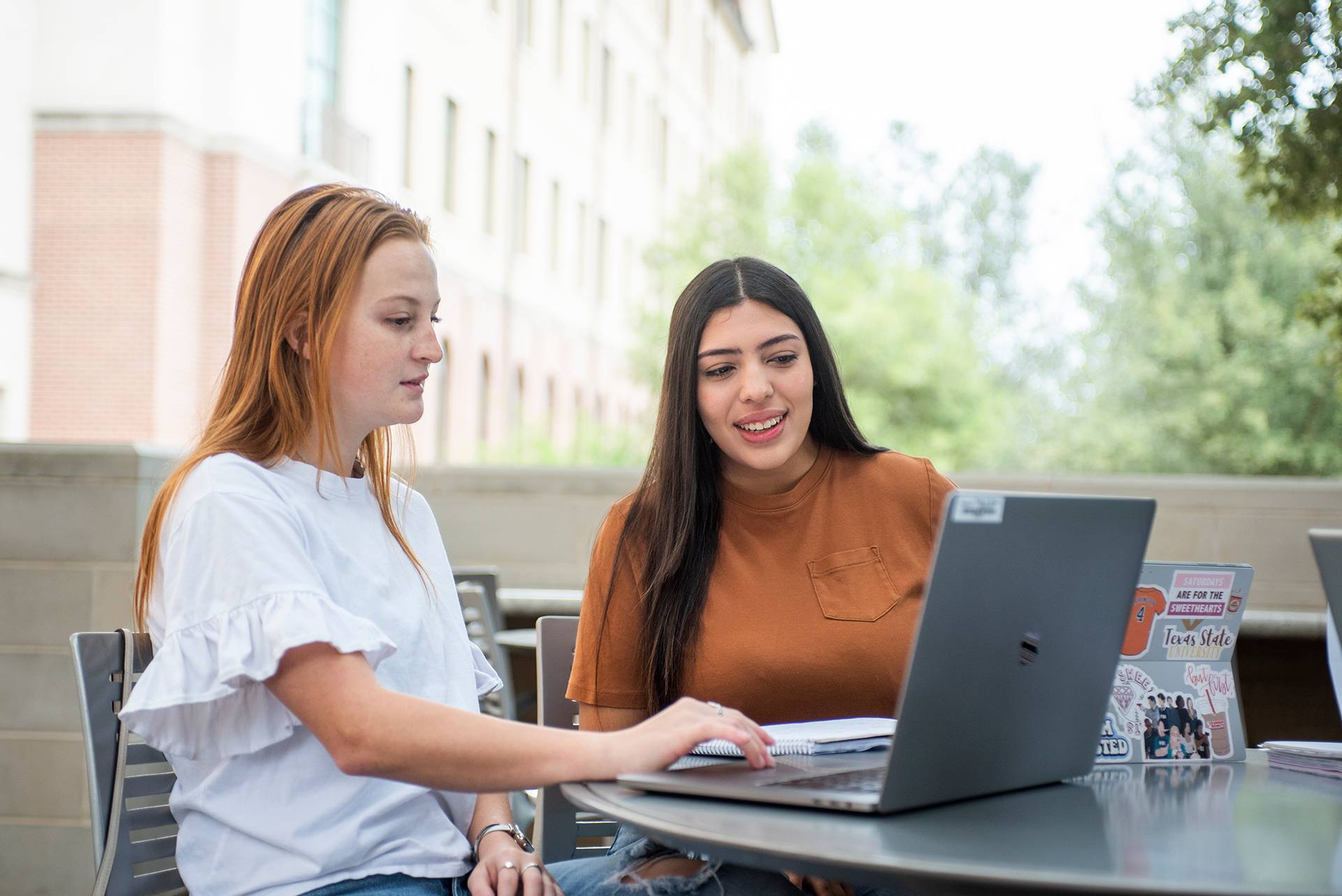 Students sitting at a table and working on a laptop