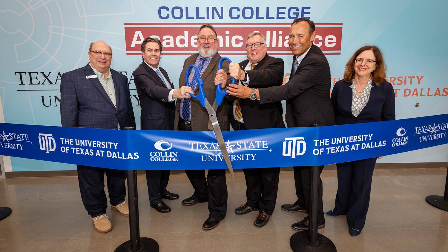 A group of people posing for a ribbon cutting photo