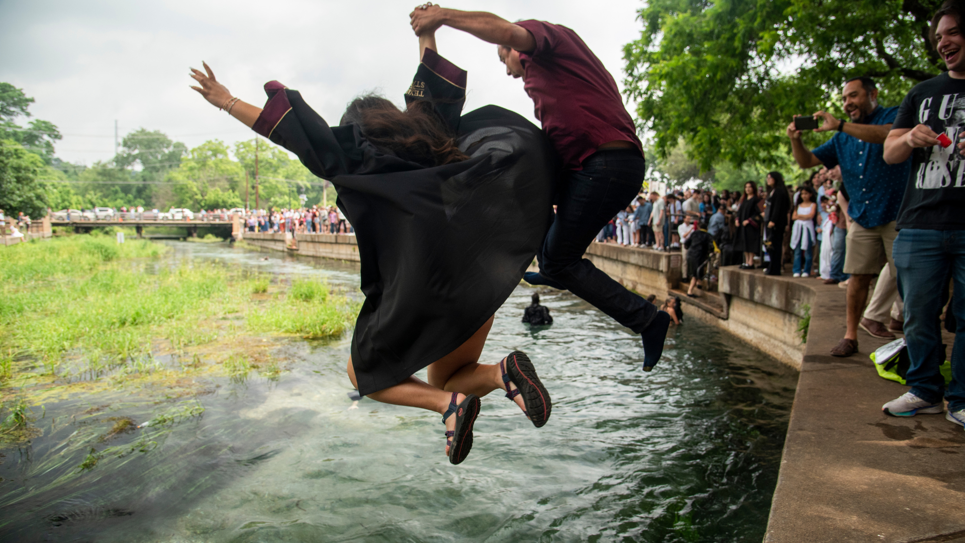 TXST student celebrating graduation with a river jump with parent
