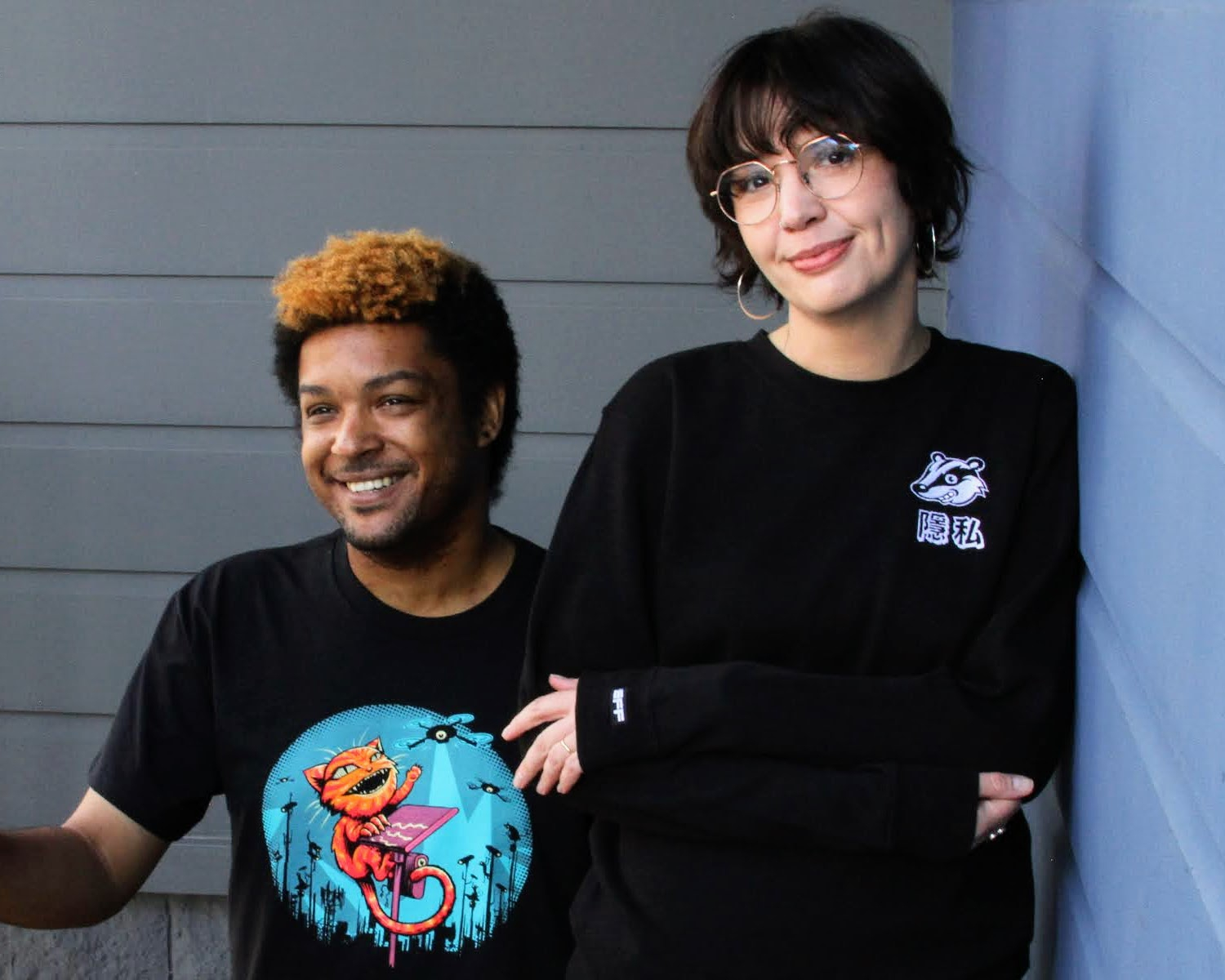 A person wears an EFF Claw Back member t-shirt on the left. A person on the right wears a black sweatshirt with the Privacy Badger mascot on the chest.