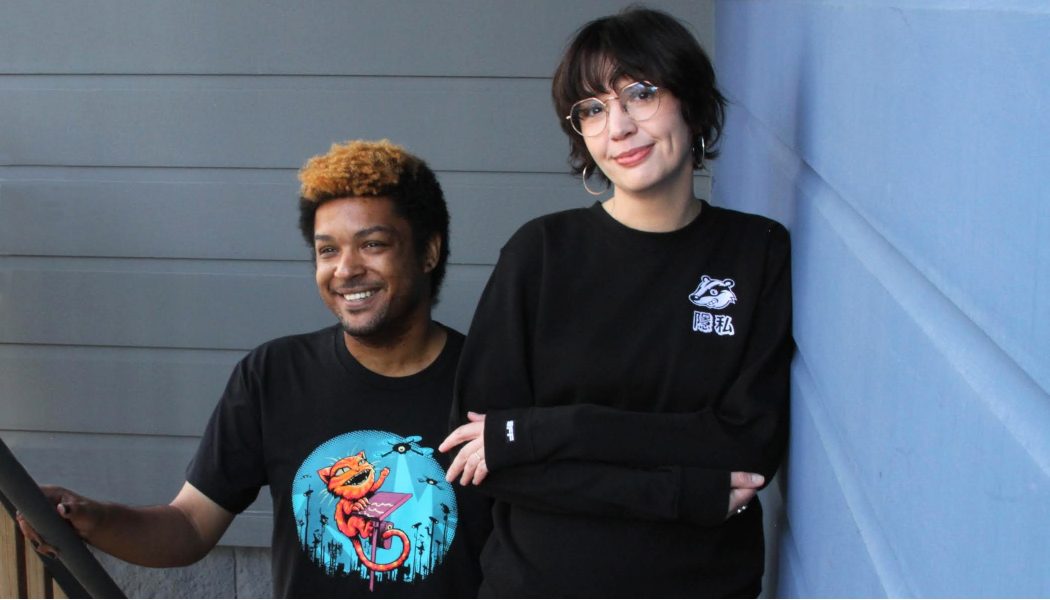 A person wears an EFF Claw Back member t-shirt on the left. A person on the right wears a black sweatshirt with the Privacy Badger mascot on the chest.