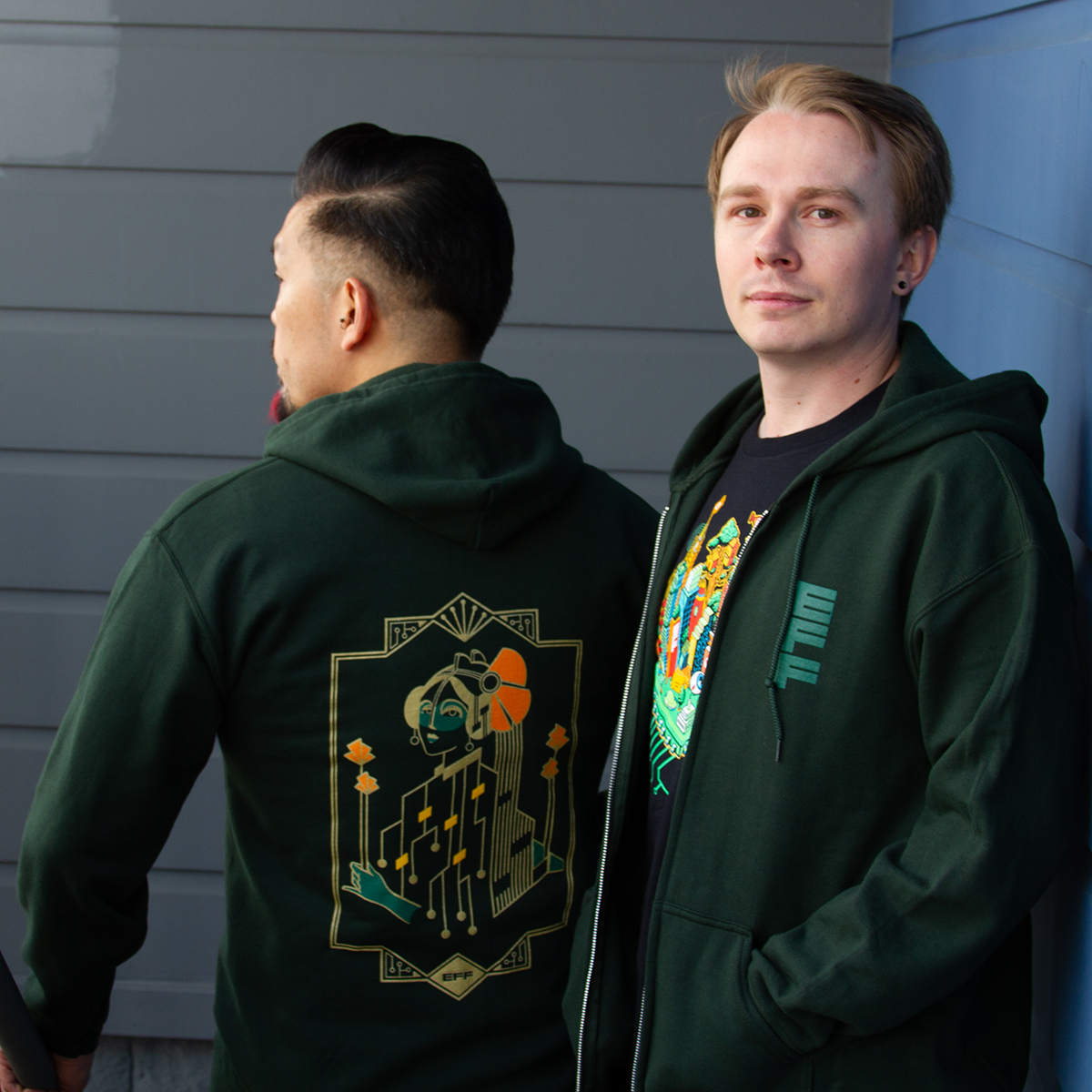 Two people wearing EFF's green Motherboard Hooded Sweatshirt