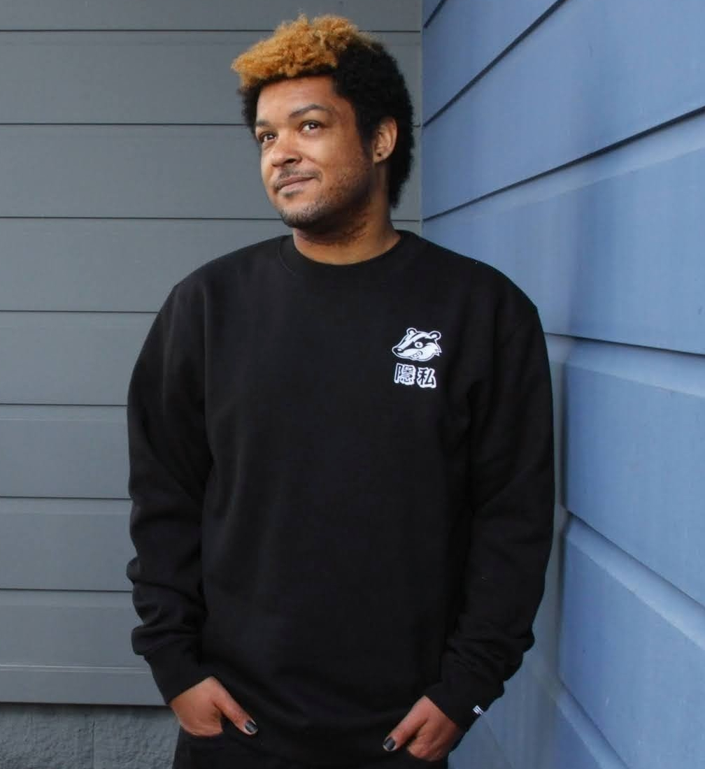 A person wearing a black sweatshirt with an embroidered Privacy Badger mascot on the chest over the characters for ‘privacy” in Traditional Chinese.