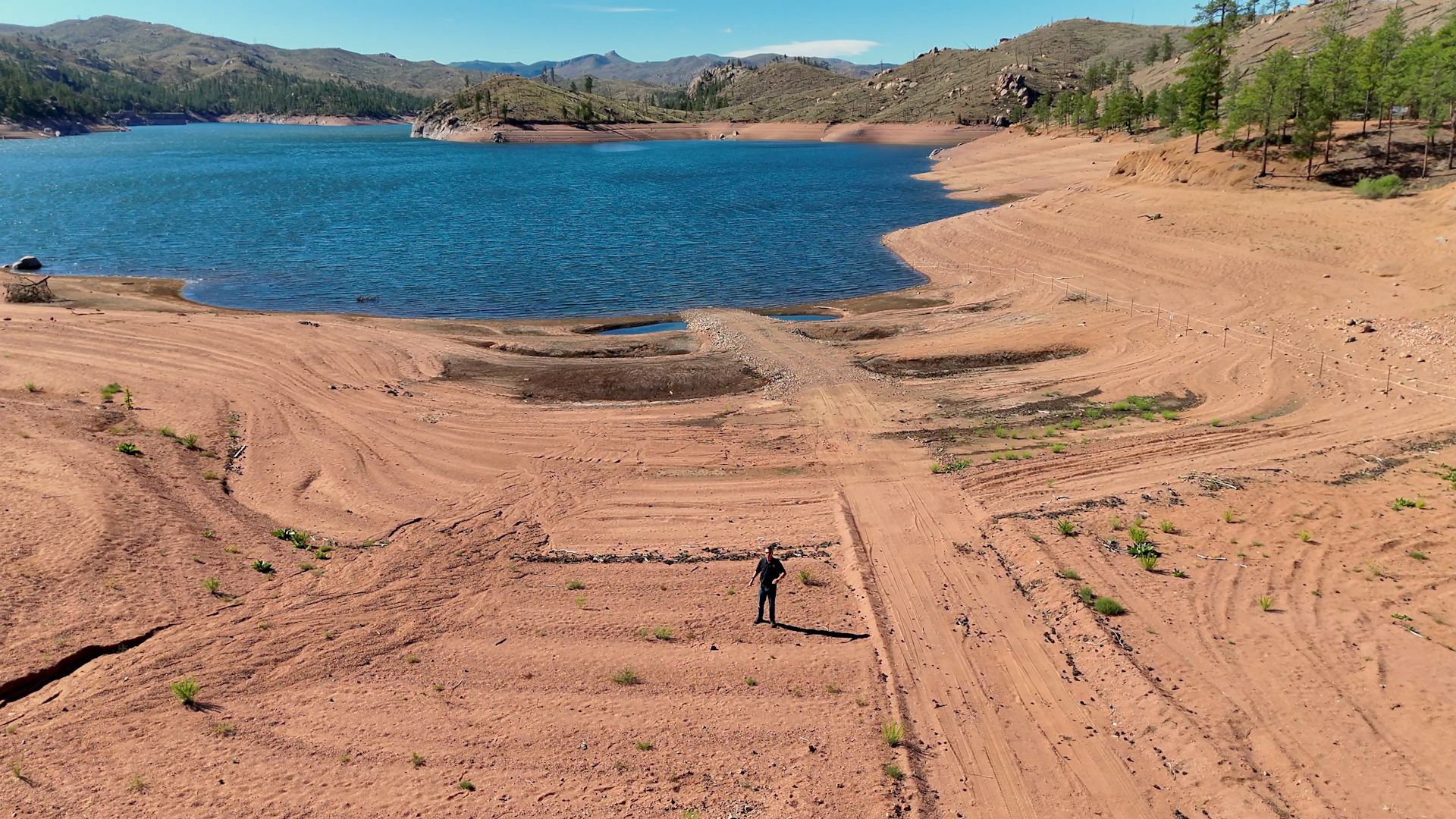 A person on a bare bank of a reservoir.