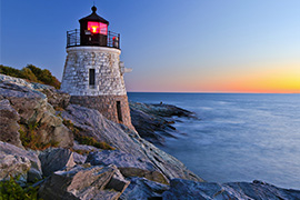 A lighthouse on the rocky coast of Rhode Island at sunset