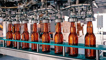 Brown glass beer bottles are filled and capped in a factory