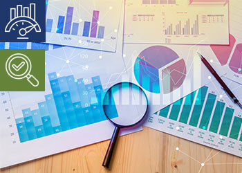 A magnifying glass and a pen sit on top of printed data tables and charts.