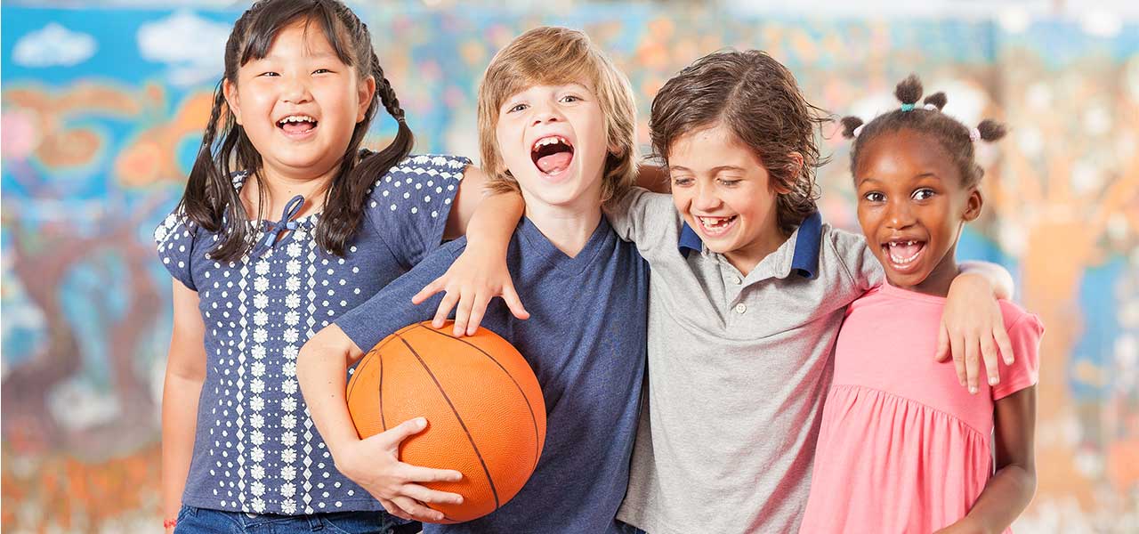 Four laughing children holding a basketball