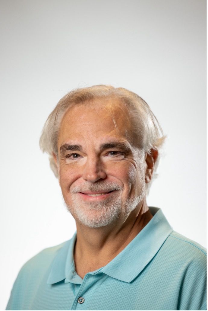 A professional photo of Joe Wingbermuehle, smiling at the camera and wearing a light blue polo shirt.