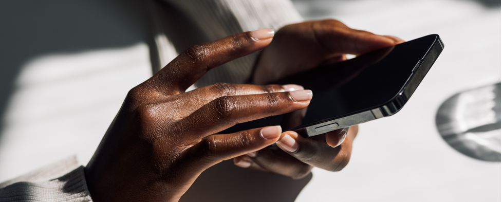 An African American woman types on her cell phone.