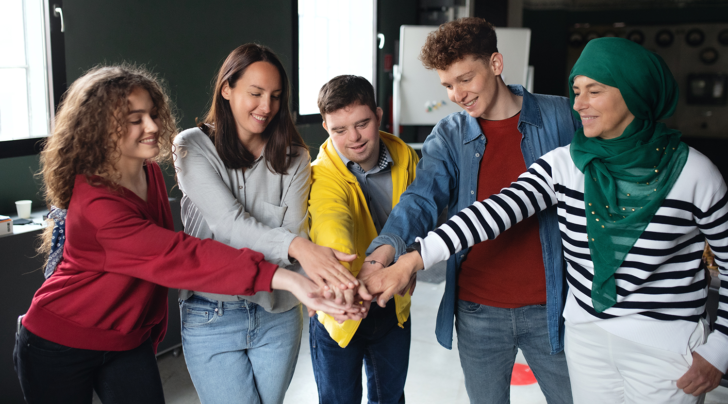 A group of individuals placing their hands together in celebration.