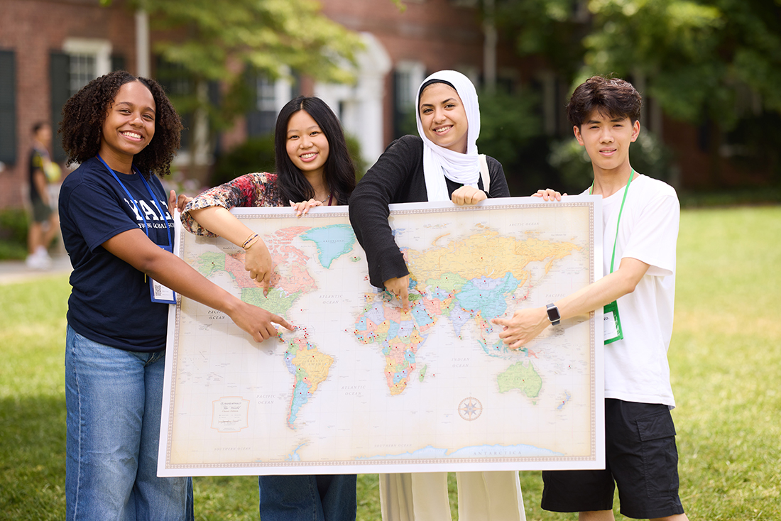 a photo of students pointing to a world map