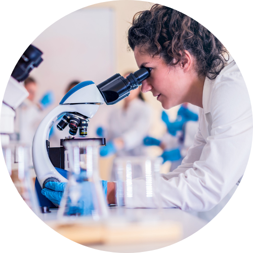 Woman in a lab coat looking through a microscope in a laboratory setting.