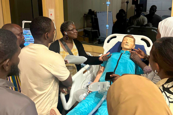 Photo of a group of learners around an adult medical mannequin from the AIRS initiative.