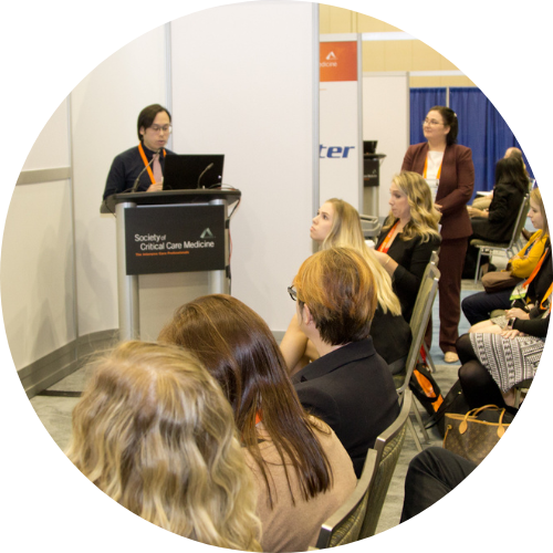 Photo of a Research Snapshot Theater, with a person presenting at a podium and seated attendees watching.