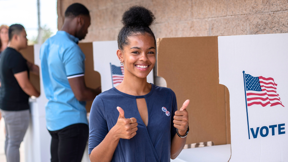 Young woman giving thumbs up at polling place