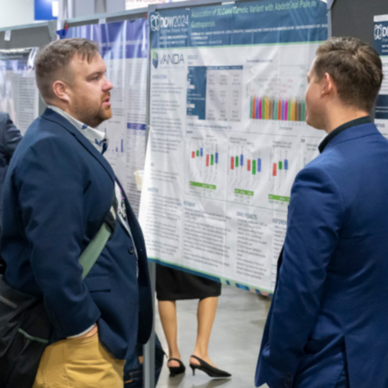 Two attendees discuss a poster at DDW